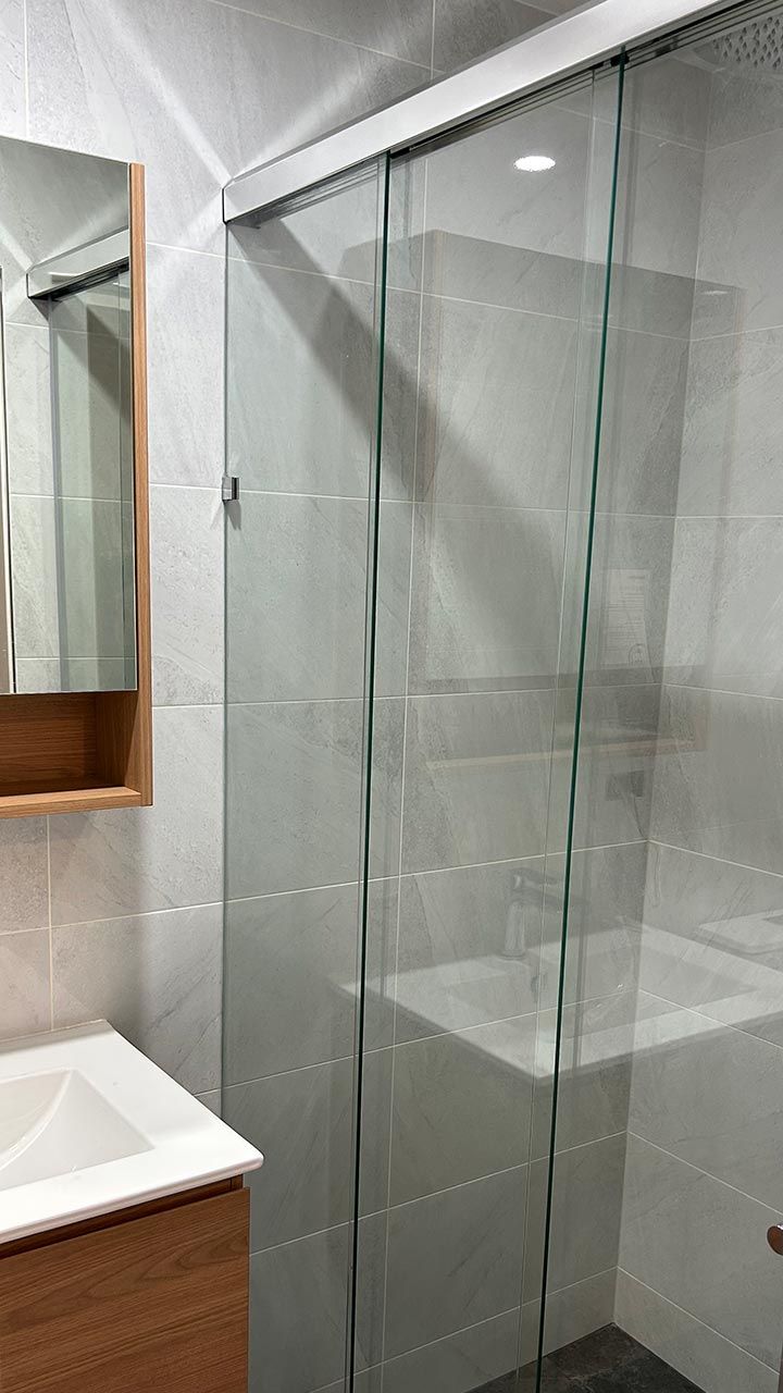 Framed glass shower screen with sliding door entry by Thomo's Home Improvements